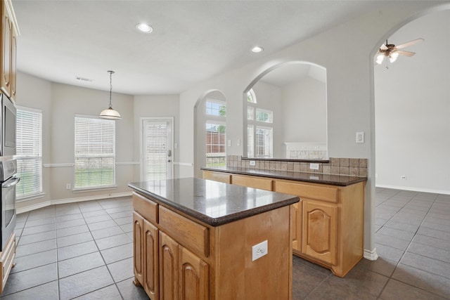 kitchen featuring dark tile patterned floors, a center island, and a wealth of natural light