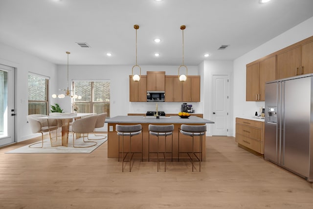 17546 Sequoia Dr, Dallas, TX 75252 - kitchen featuring pendant lighting, appliances with stainless steel finishes, light wood finished floors, and visible vents
