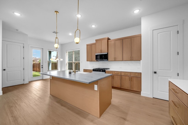 17546 Sequoia Dr, Dallas, TX 75252 - kitchen with stove, stainless steel microwave, a sink, light wood-style flooring, and hanging light fixtures