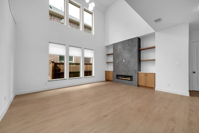 17546 Sequoia Dr, Dallas, TX 75252 - unfurnished living room featuring light wood-style floors, visible vents, baseboards, and a towering ceiling