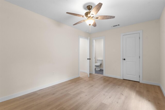 unfurnished bedroom with light wood-type flooring, baseboards, ensuite bathroom, and ceiling fan