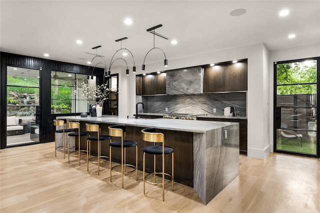4280 Shorecrest Dr, Dallas, TX 75209 - kitchen with modern cabinets, decorative backsplash, a spacious island, light wood-type flooring, and a breakfast bar area