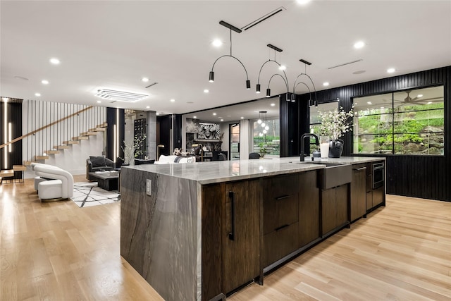 4280 Shorecrest Dr, Dallas, TX 75209 - kitchen with modern cabinets, a spacious island, open floor plan, dark brown cabinetry, and light wood-style floors