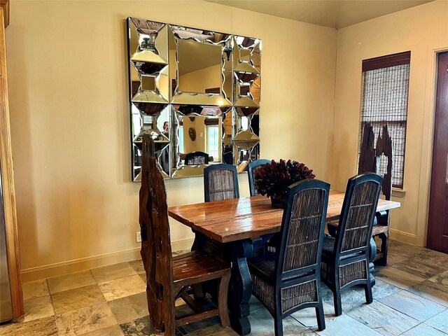 dining space featuring stone tile floors and baseboards
