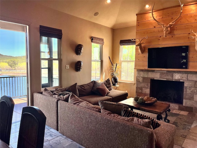 living room featuring a fireplace, vaulted ceiling, recessed lighting, and stone finish flooring