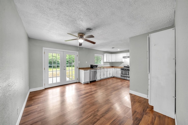 unfurnished living room featuring french doors, a ceiling fan, dark wood-style flooring, a textured ceiling, and baseboards