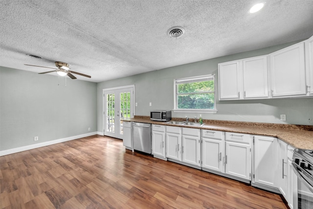 kitchen featuring white cabinets, a ceiling fan, stainless steel appliances, and a textured ceiling