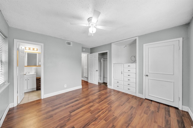 unfurnished bedroom with a textured ceiling, baseboards, wood finished floors, and visible vents