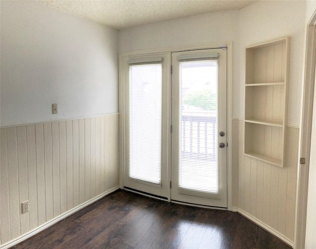 entryway with wooden walls, wainscoting, a textured ceiling, and dark wood-style floors