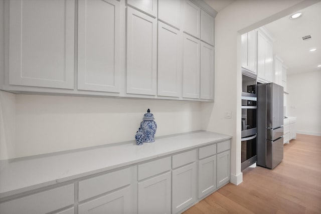 kitchen with baseboards, light wood-type flooring, light countertops, recessed lighting, and appliances with stainless steel finishes