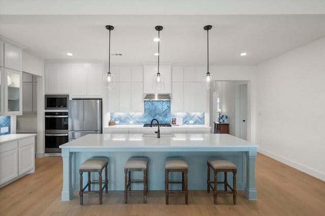 kitchen featuring light wood-style flooring, backsplash, white cabinetry, and stainless steel appliances