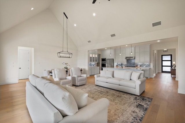 living room featuring visible vents, recessed lighting, light wood-style floors, and high vaulted ceiling