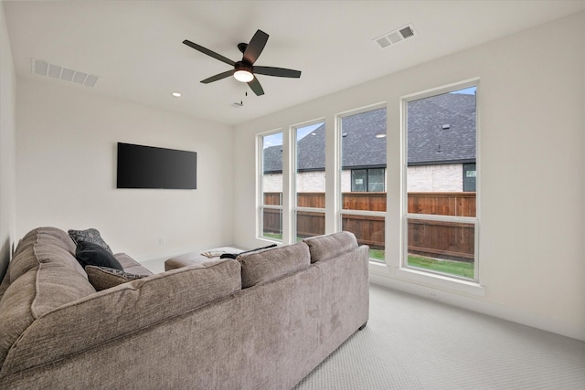 living area with light colored carpet, ceiling fan, and visible vents