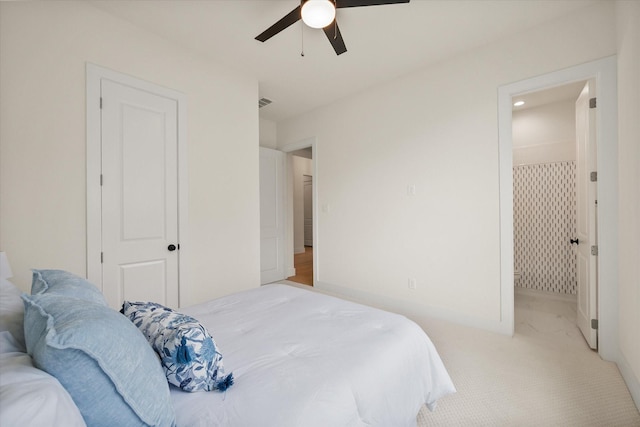 bedroom with a ceiling fan, light carpet, and ensuite bath