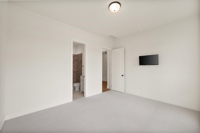unfurnished bedroom featuring connected bathroom, light colored carpet, baseboards, and visible vents