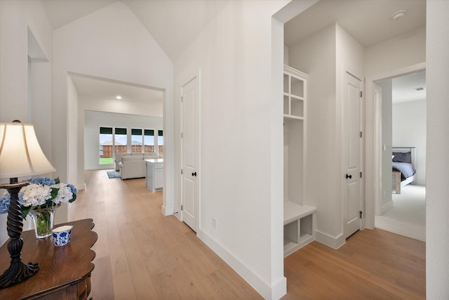 hallway with light wood-type flooring and lofted ceiling