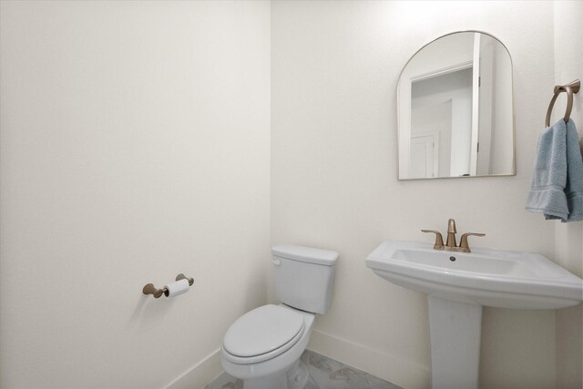 bathroom featuring a sink, baseboards, and toilet