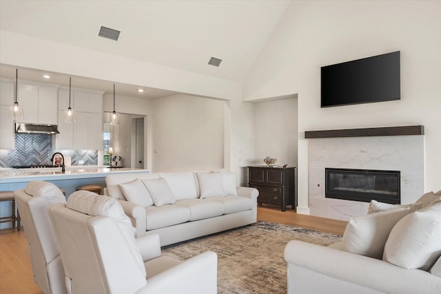 living area with recessed lighting, high vaulted ceiling, visible vents, and light wood-style floors