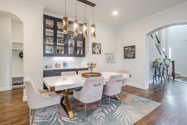 dining space featuring arched walkways, recessed lighting, baseboards, dark wood-type flooring, and ornamental molding