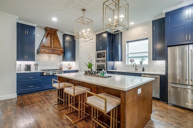 kitchen with appliances with stainless steel finishes, a kitchen breakfast bar, blue cabinetry, a center island, and custom exhaust hood