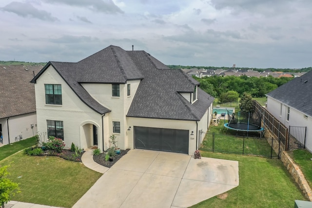 french country home with fence private yard, a front yard, roof with shingles, concrete driveway, and an attached garage