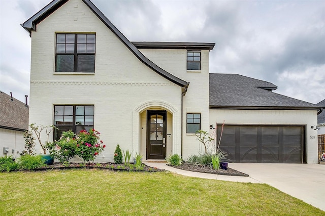 view of front of house featuring a garage, a front yard, roof with shingles, brick siding, and driveway