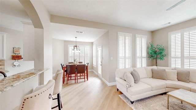 living room featuring baseboards, visible vents, an inviting chandelier, and light wood-type flooring