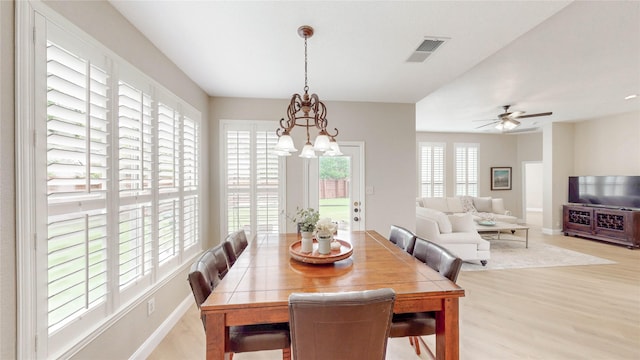 dining room with baseboards, ceiling fan with notable chandelier, visible vents, and wood finished floors