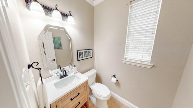 bathroom featuring toilet, vanity, baseboards, and wood finished floors