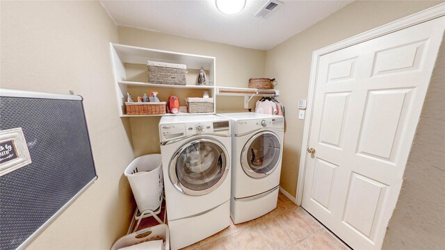 clothes washing area featuring laundry area, light tile patterned floors, visible vents, and washing machine and dryer