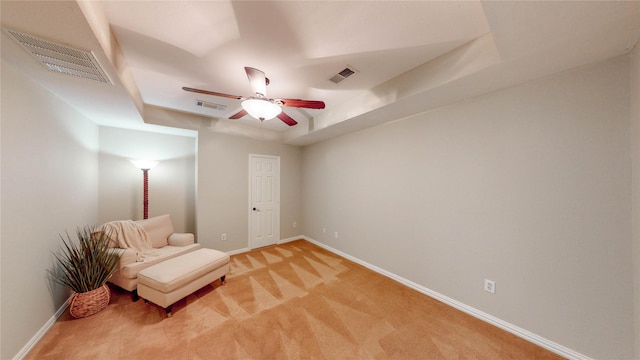 sitting room featuring light carpet, baseboards, a ceiling fan, and a raised ceiling