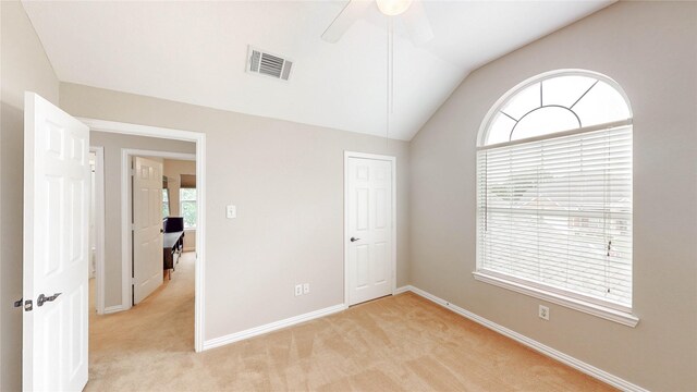 unfurnished bedroom with vaulted ceiling, light carpet, baseboards, and visible vents