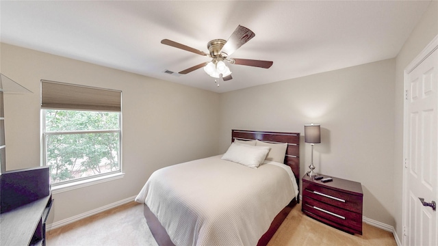 bedroom featuring light colored carpet, baseboards, and a ceiling fan