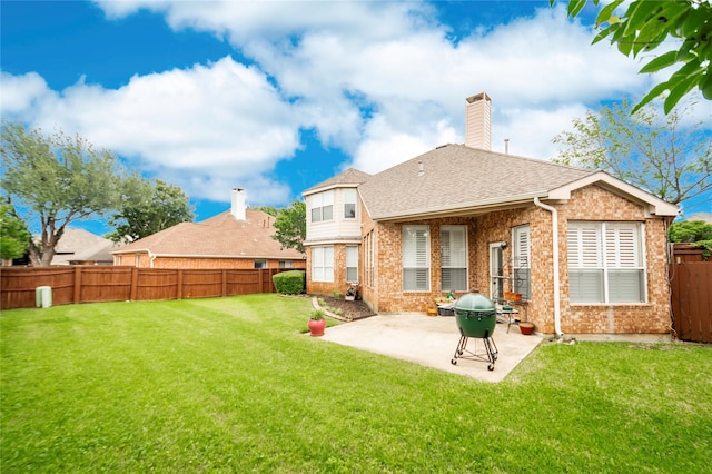 rear view of property featuring a fenced backyard, a yard, roof with shingles, brick siding, and a patio area