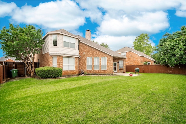 rear view of property with a chimney, a patio, brick siding, and a fenced backyard