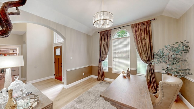 home office with lofted ceiling, wood finished floors, arched walkways, a notable chandelier, and baseboards