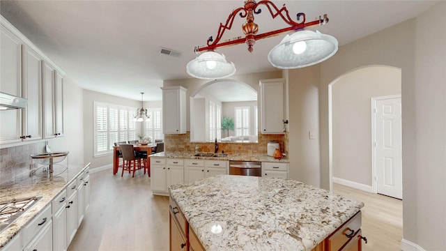 kitchen with arched walkways, light wood-type flooring, and visible vents