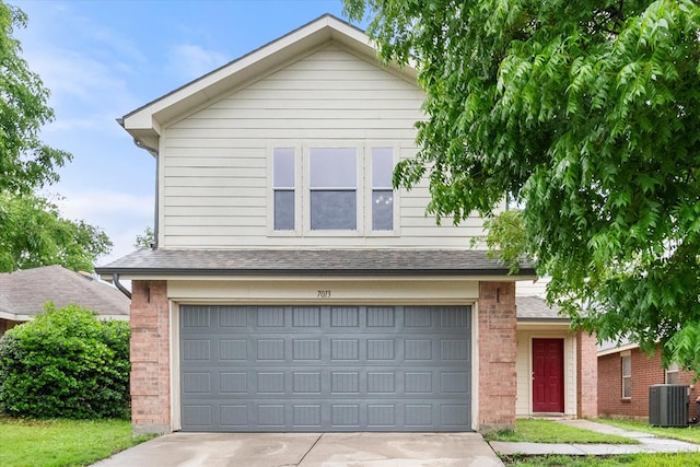 traditional-style home featuring roof with shingles, brick siding, a garage, cooling unit, and driveway