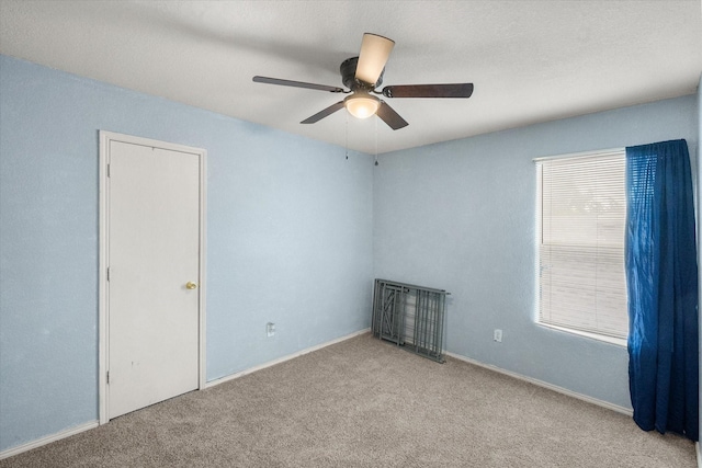 unfurnished room with carpet flooring, ceiling fan, and baseboards