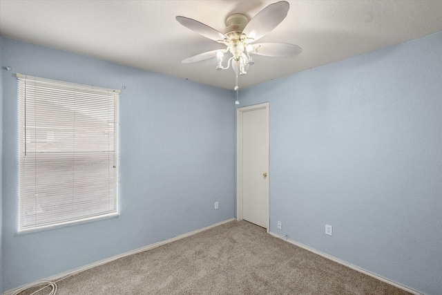empty room featuring baseboards, a ceiling fan, and light colored carpet