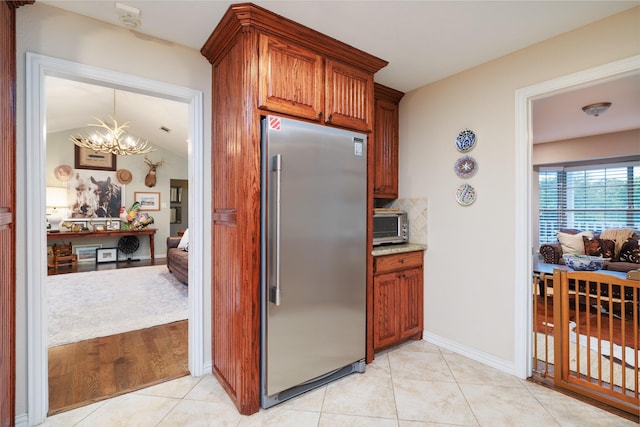 11330 Hillcrest Rd, Dallas, TX 75230 - kitchen with light tile patterned floors, high end fridge, a notable chandelier, light stone countertops, and decorative backsplash