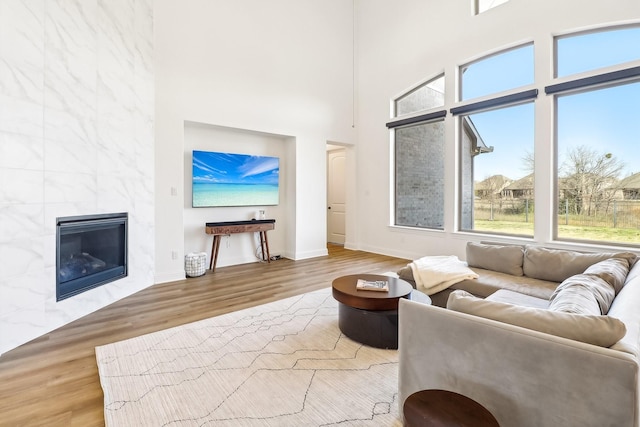 311 Misty Ln, Argyle, TX 76226 - living area featuring a tiled fireplace, baseboards, wood finished floors, and a towering ceiling
