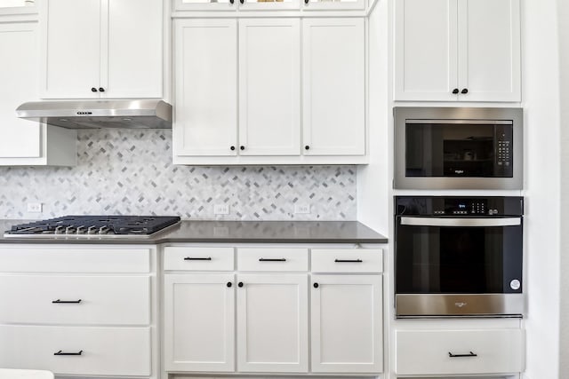 311 Misty Ln, Argyle, TX 76226 - kitchen featuring dark countertops, appliances with stainless steel finishes, white cabinetry, decorative backsplash, and under cabinet range hood