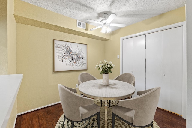 dining space featuring ceiling fan, a textured ceiling, baseboards, wood finished floors, and visible vents