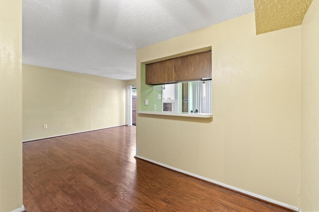 unfurnished room with baseboards, dark wood-style flooring, and a textured ceiling
