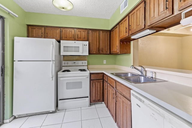 kitchen featuring a sink, brown cabinets, and white appliances