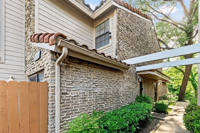 view of side of home with fence and stone siding