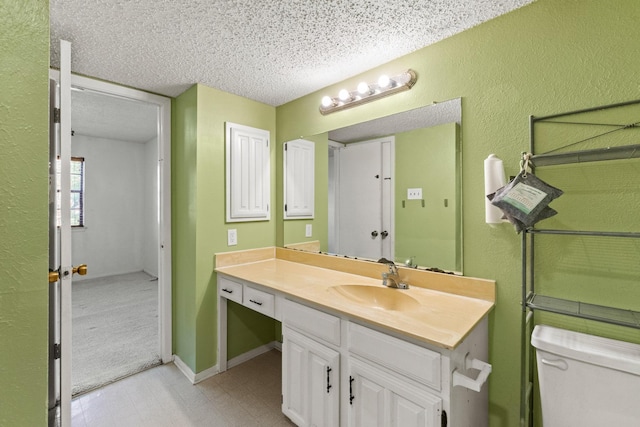bathroom with vanity, a textured wall, toilet, and a textured ceiling