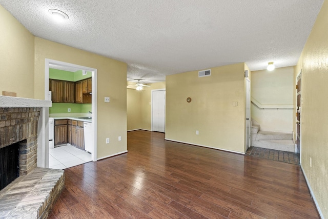unfurnished living room featuring wood finished floors, a fireplace, a textured ceiling, and visible vents