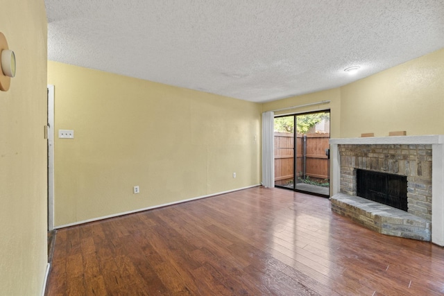 unfurnished living room with baseboards, a textured ceiling, wood finished floors, and a fireplace
